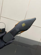 Black heel underside of a slingback flat with gold emblem branding on the footbed