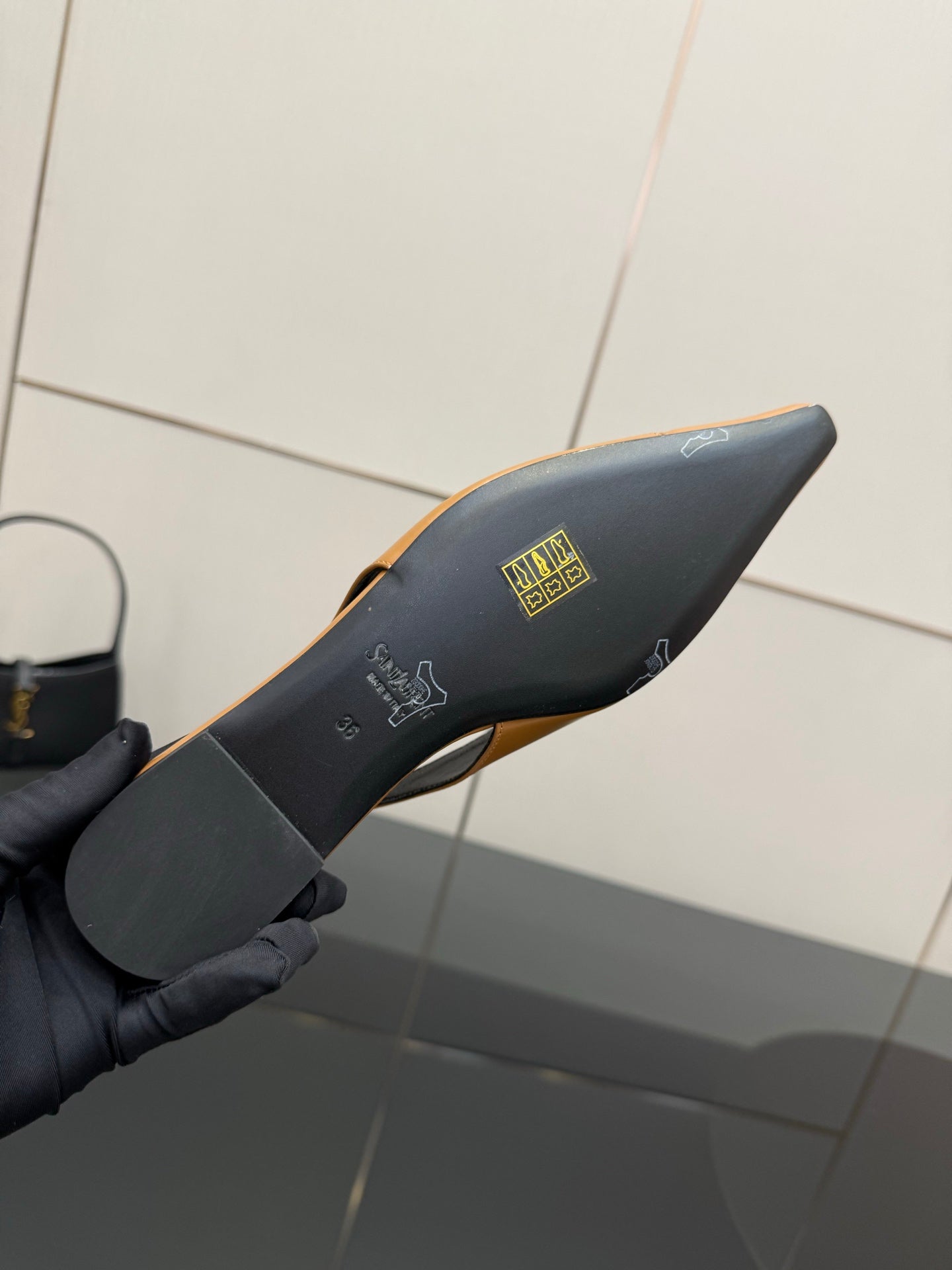 Black heel underside of a slingback flat with gold emblem branding on the footbed