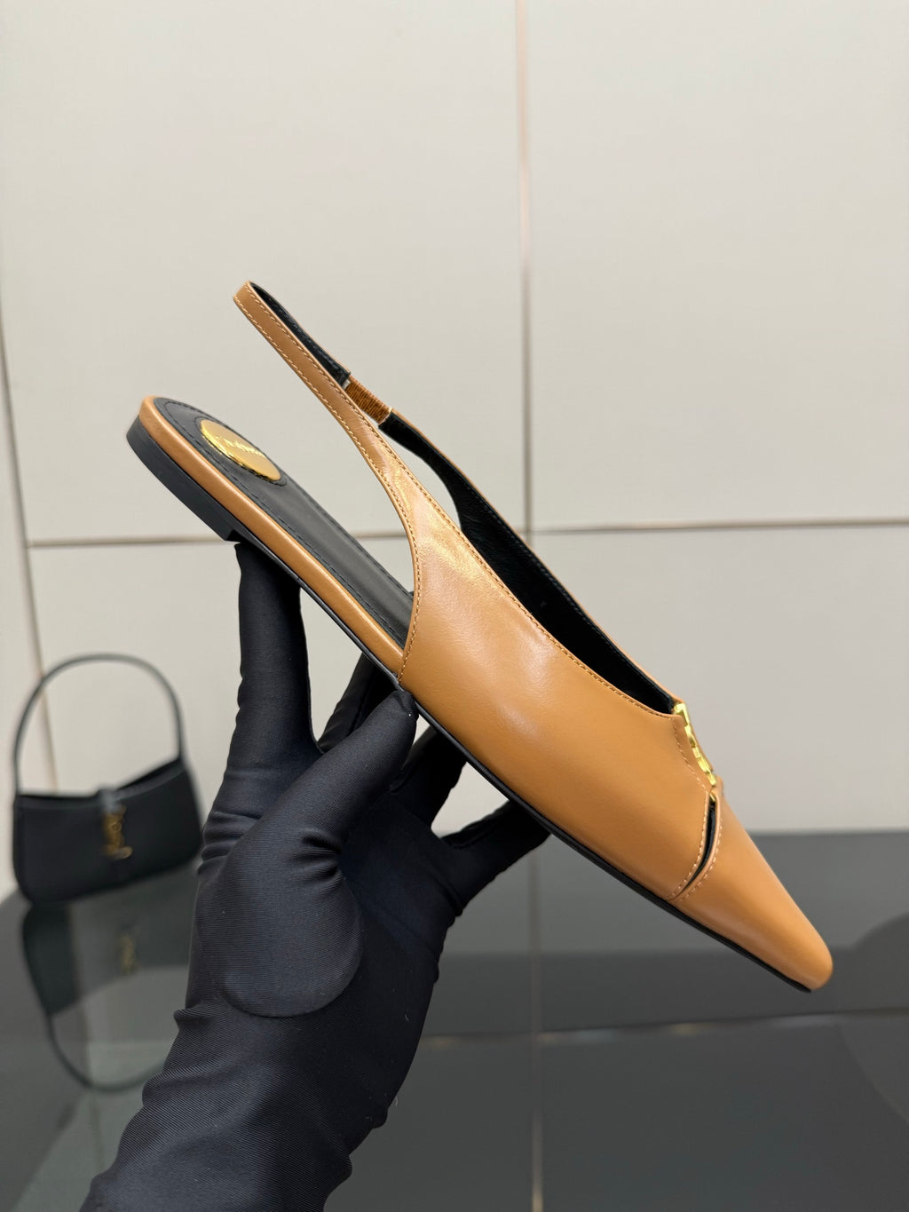 Tan pointed-toe slingback flat shown from the side, low profile and gold logo detail