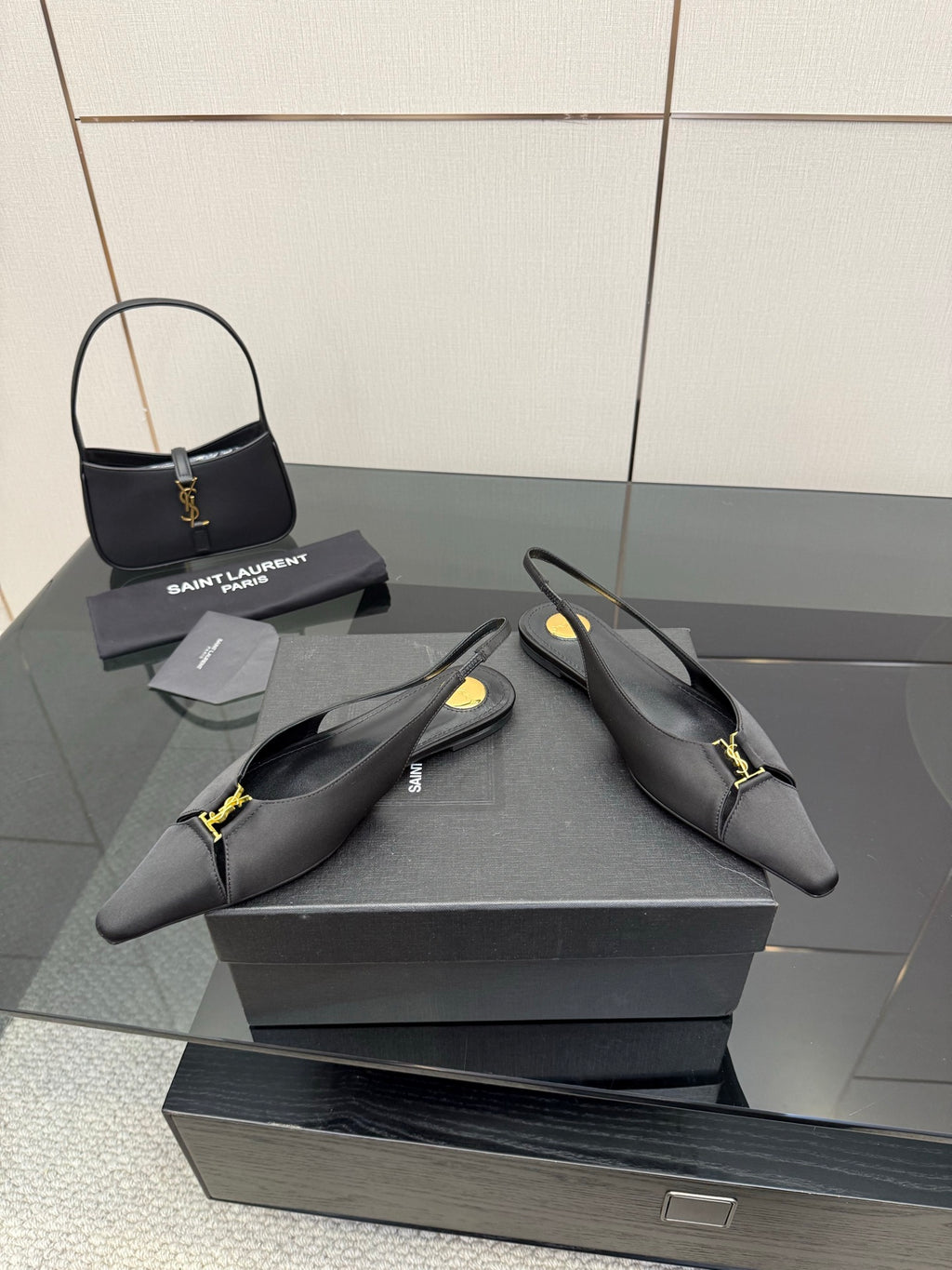 Women's black pointed-toe slingback heels with gold Y-style logo at strap, stiletto