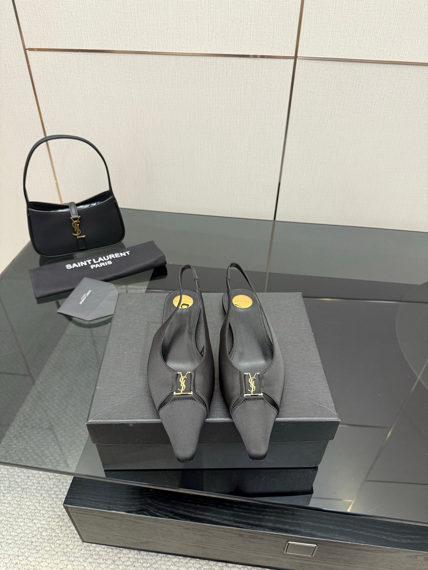 Women's black pointed-toe slingback heels with gold logo detail, stiletto heel