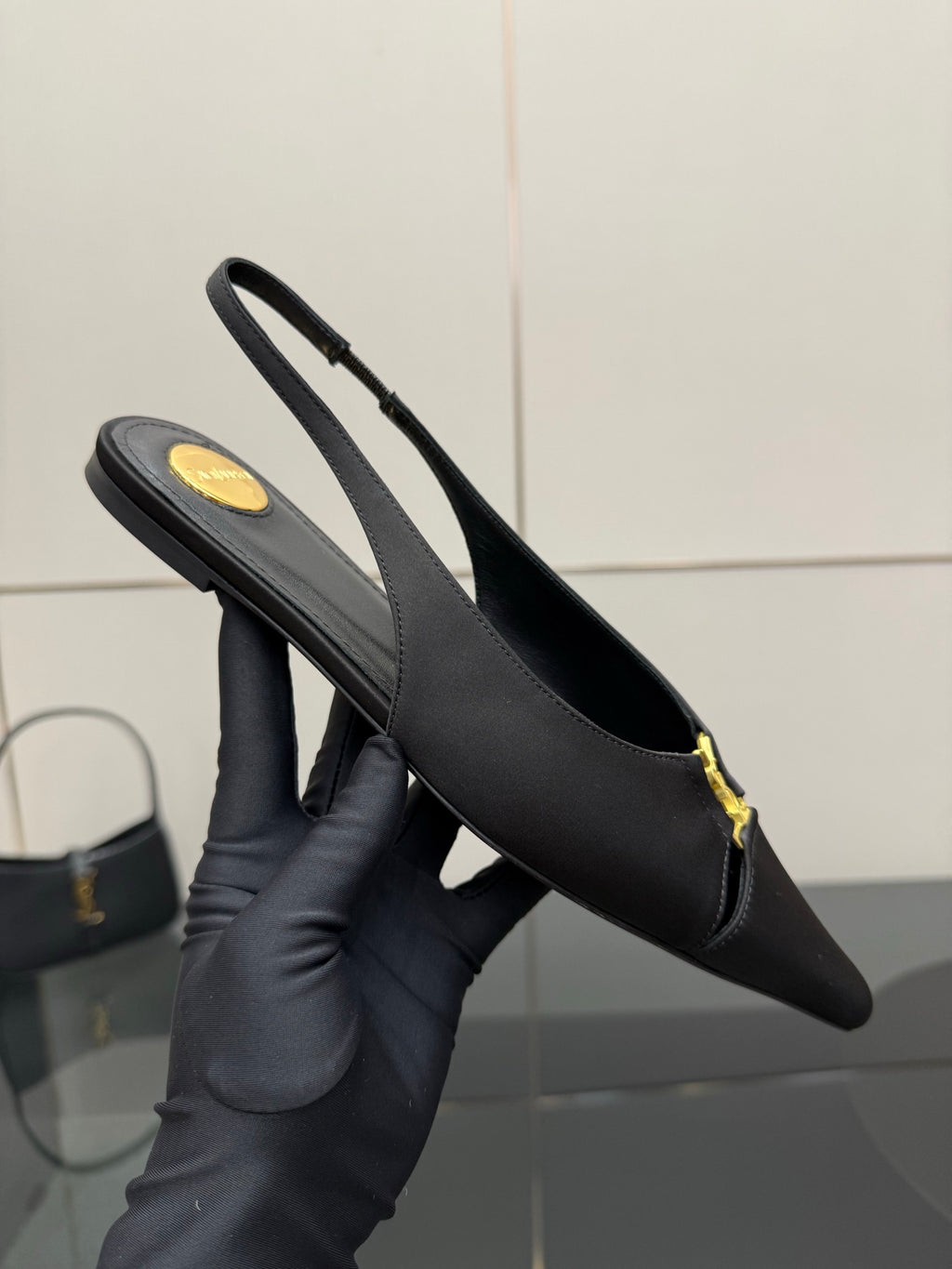 Single women's black slingback heel with stiletto heel and gold logo strap