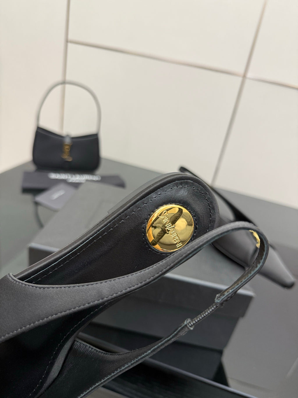 Women's black slingback heel with round gold logo medallion on outer side