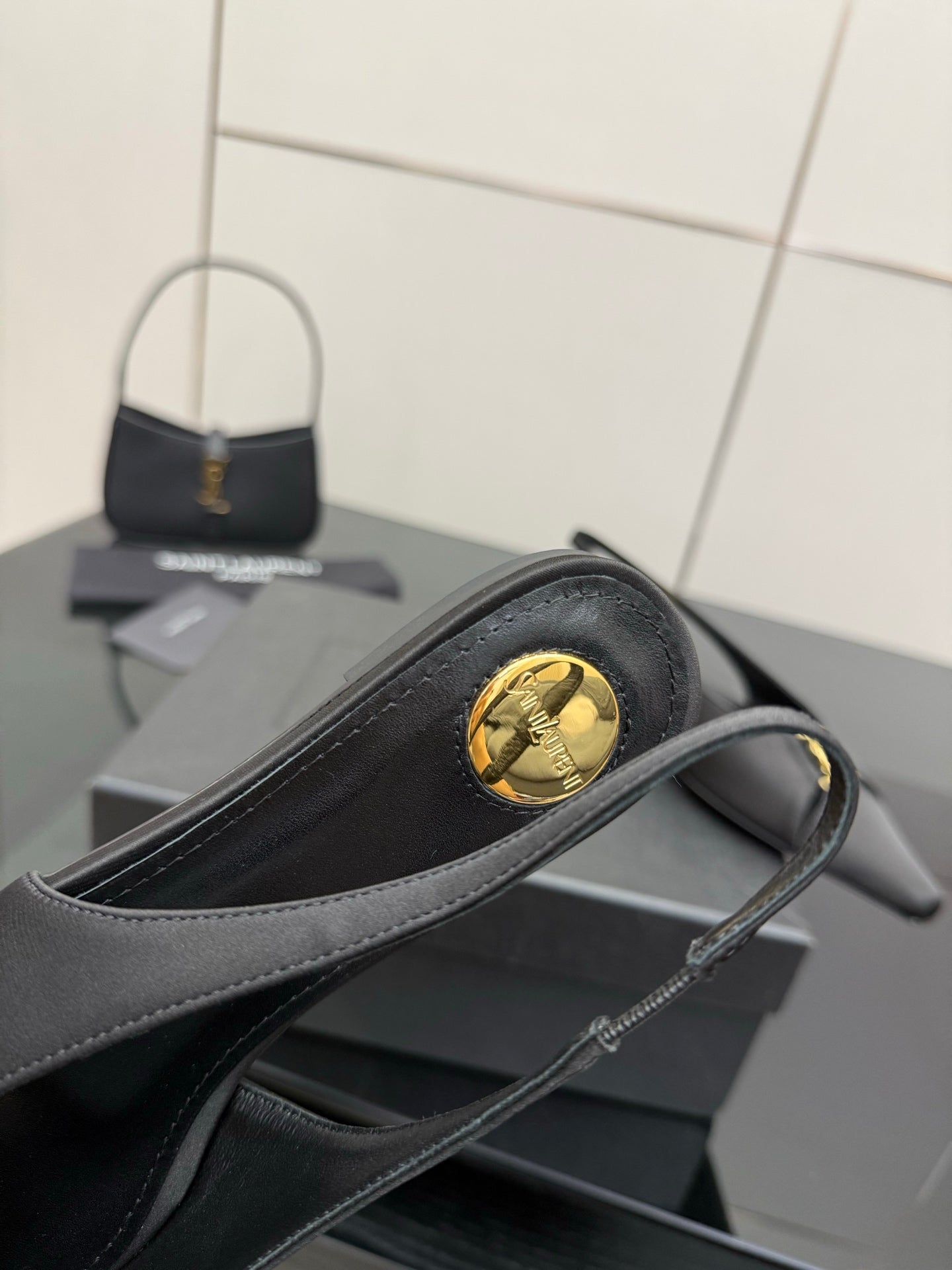 Women's black slingback heel with round gold logo medallion on outer side