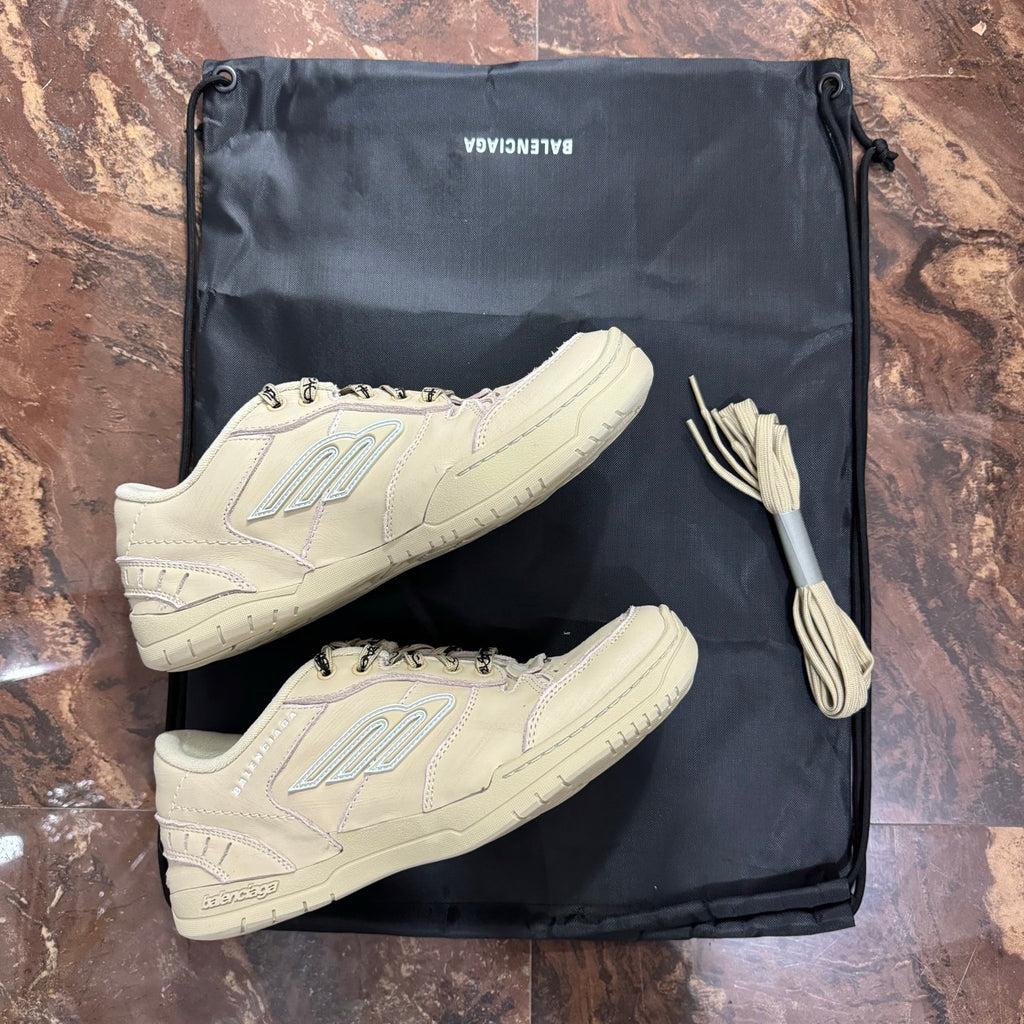 Pair of beige Balenciaga low-top sneakers with lace-up fronts in drawstring bag