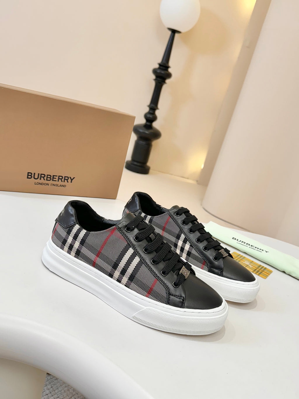 Burberry low-top sneakers with black base, tartan plaid panels, white rubber sole