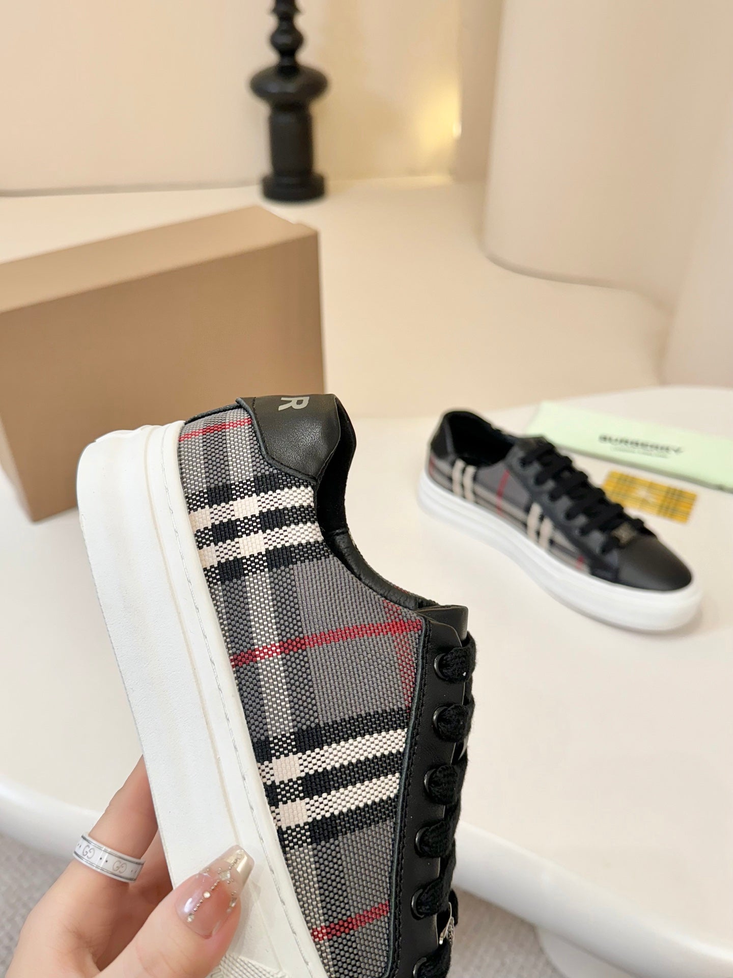 Burberry low-top sneakers close-up, plaid fabric upper with black leather edging