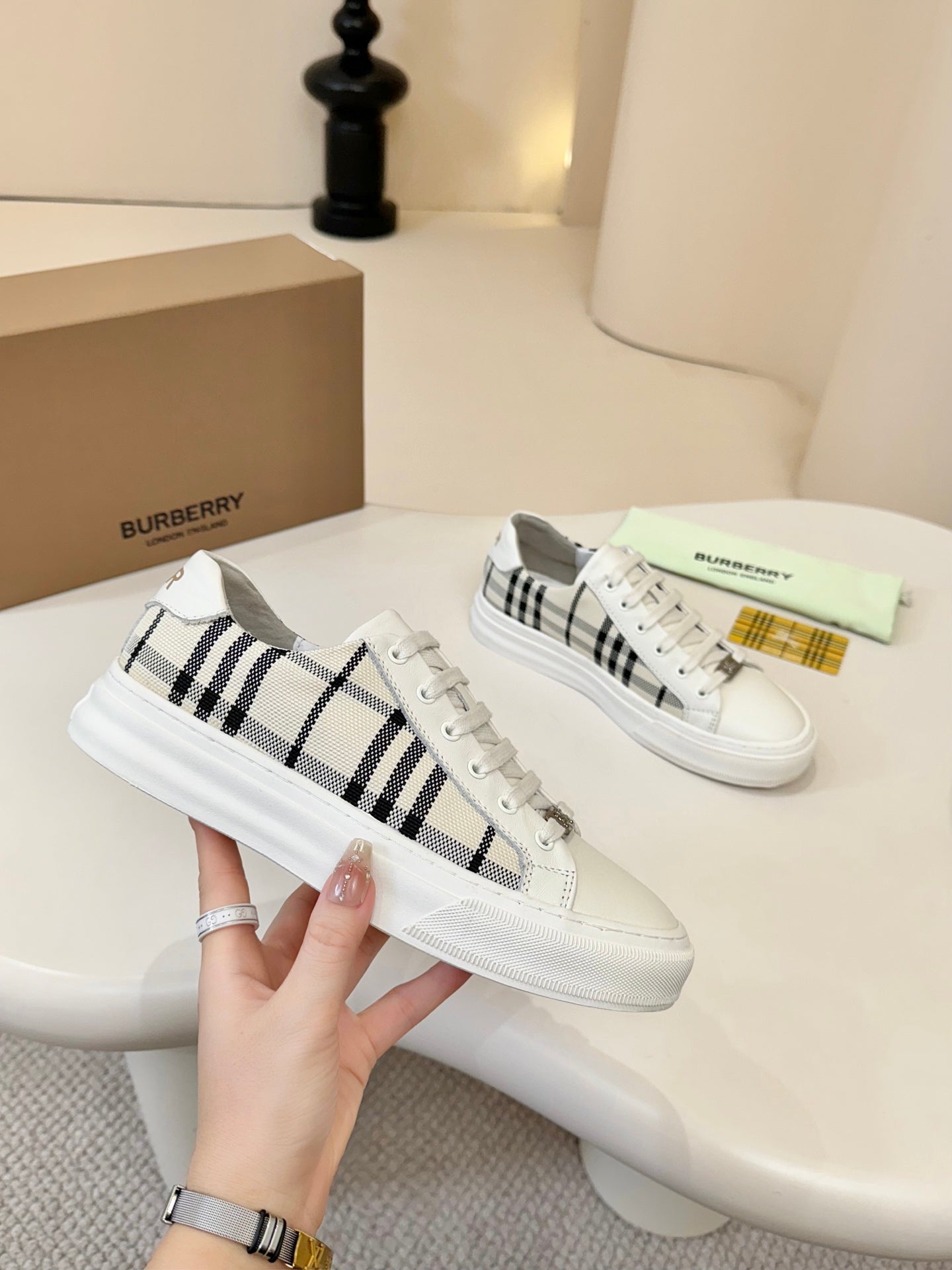 Pair of lace-up low-top sneakers with white uppers and black-and-cream check panels