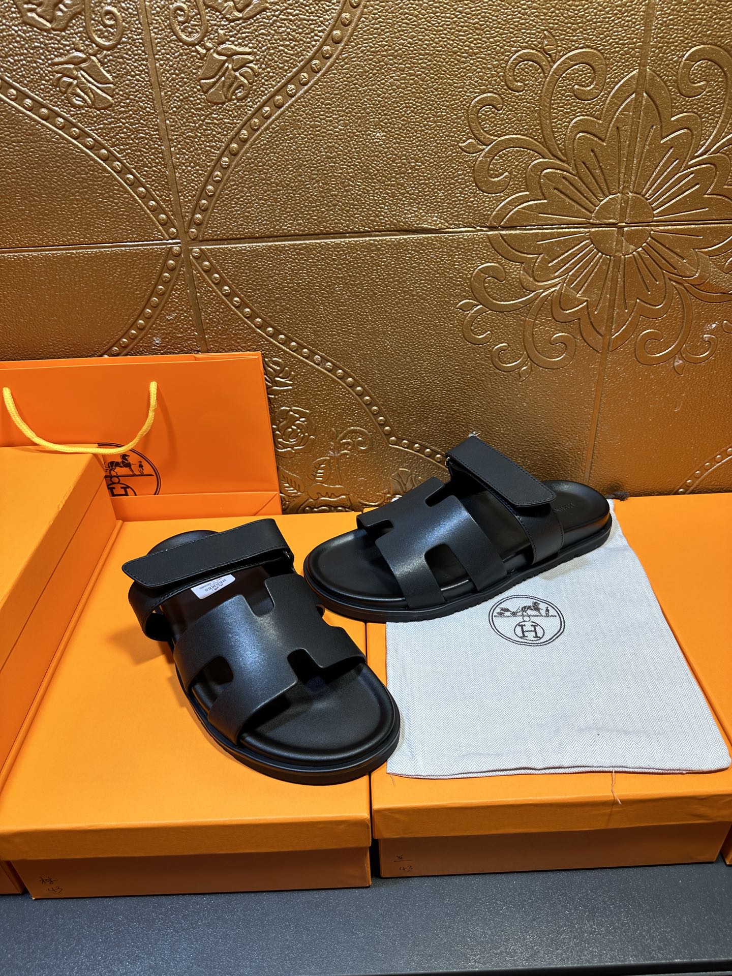 Hermes dark leather slide sandals with double straps, pair laid on cloth