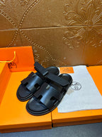 Hermes dark leather slide sandals with double straps, angled view