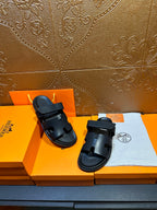 Hermes dark leather slide sandals with double straps, one sandal slightly forward