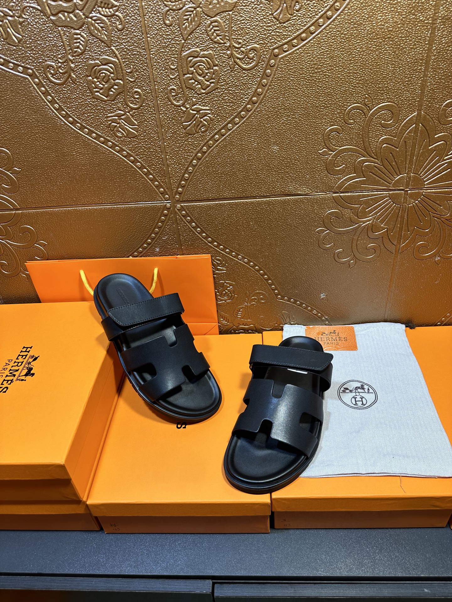 Hermes dark leather slide sandals with double straps, one sandal slightly forward