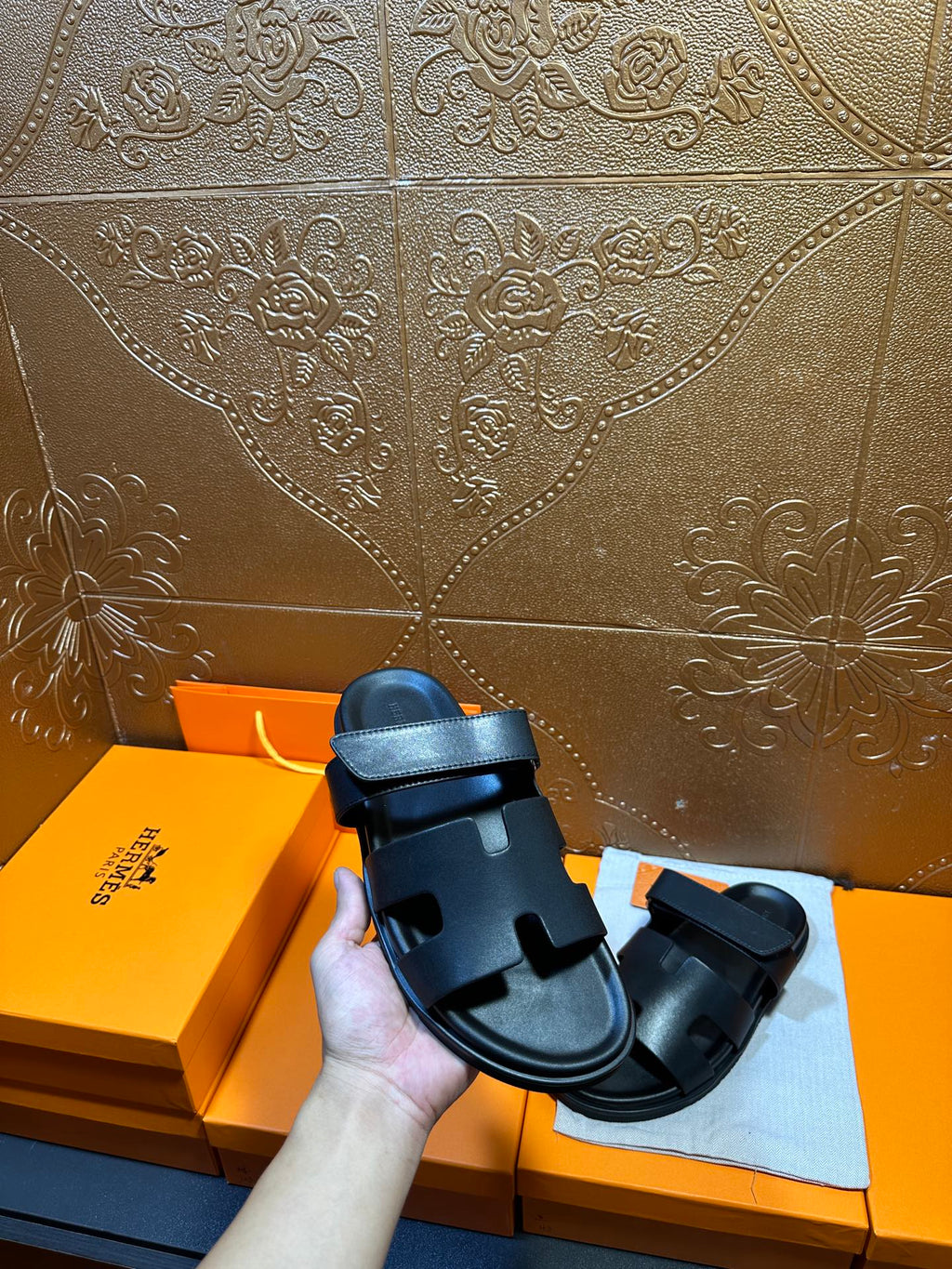 Hermes dark leather slide sandal held up, showing double strap design