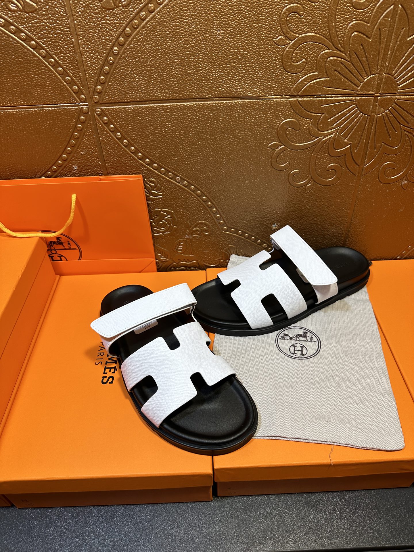 Pair of white slide sandals with black soles and H-shaped strap cutouts