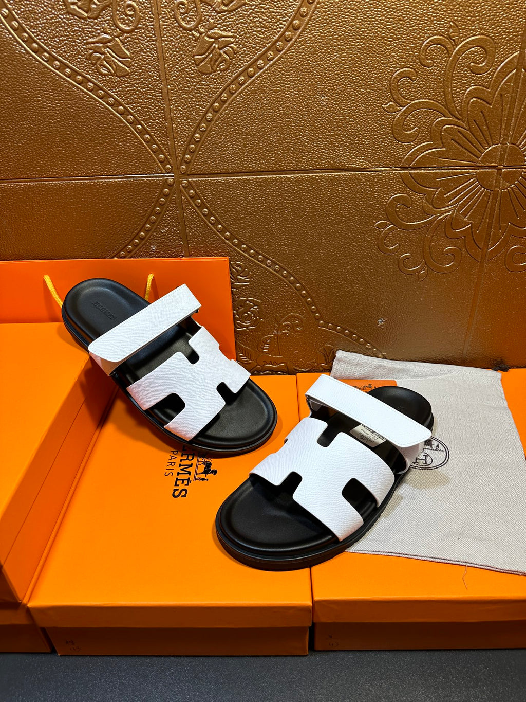 White slide sandals with black soles and wide straps with cutout openings