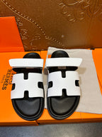 White slide sandals with black cutout details and cushioned black sole