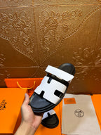 White slide sandals with black footbed, wide strap and open center details