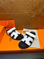 Two white slide sandals with black footbeds, stacked on a cloth accessory pouch