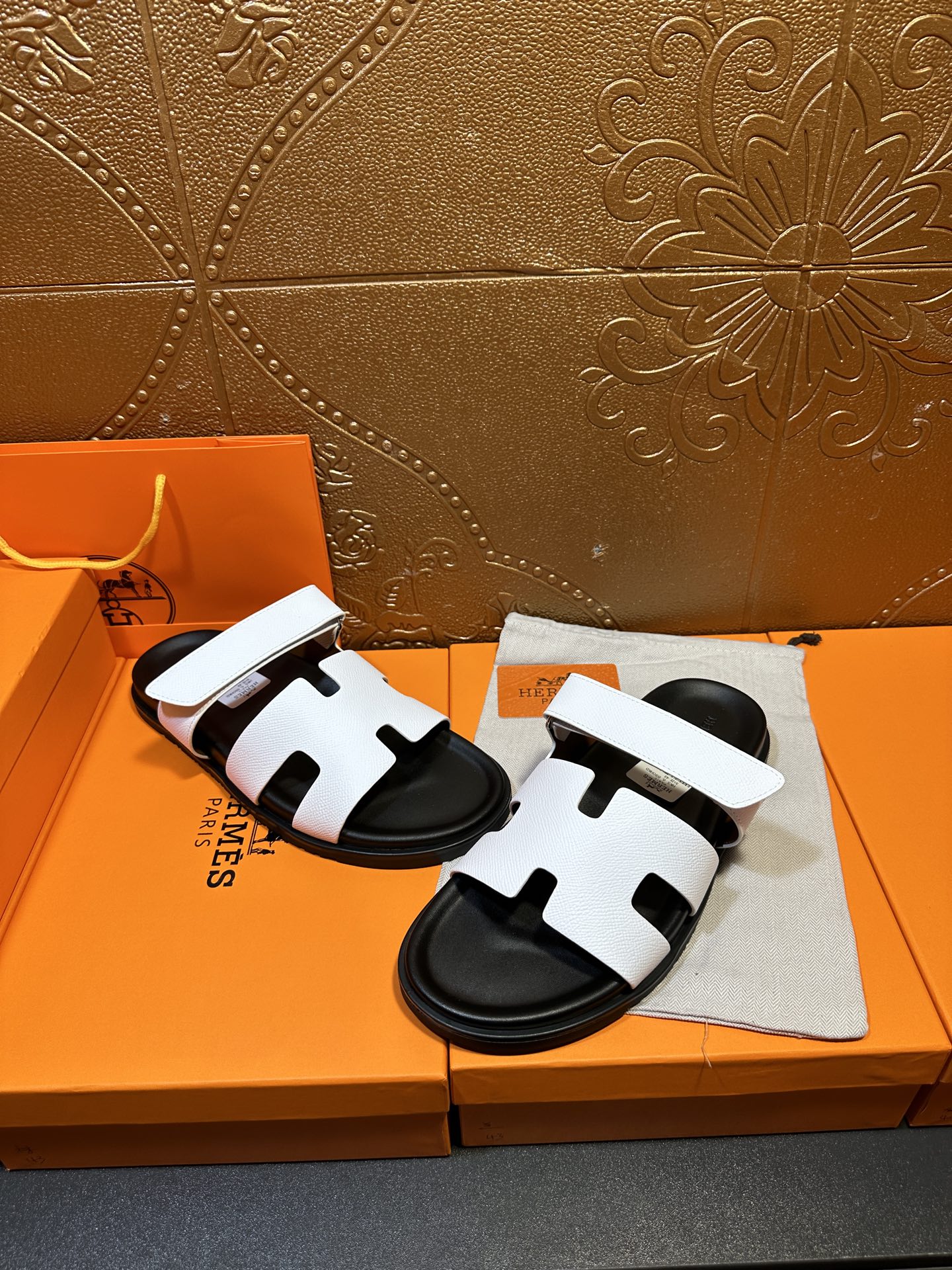Two white slide sandals with black footbeds, stacked on a cloth accessory pouch