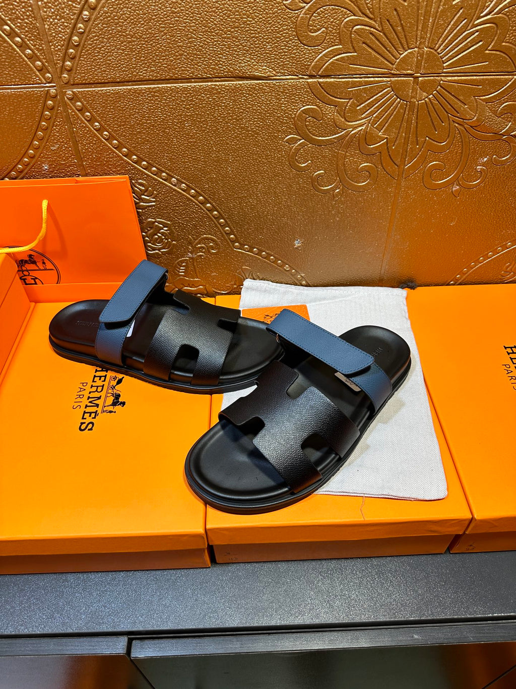 Hermes black slide sandals with blue strap, front view on box