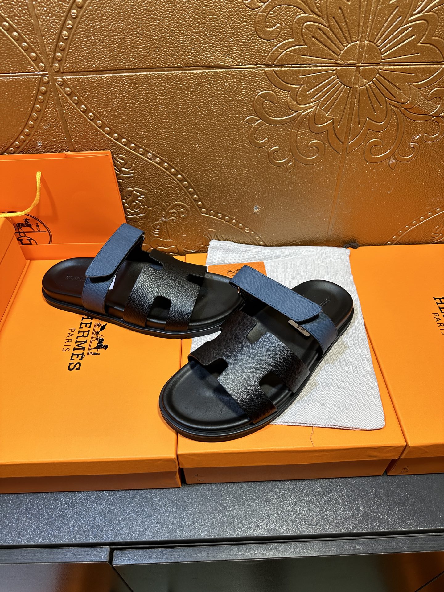 Hermes black slide sandals with blue strap, front view on box