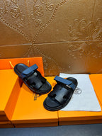 Hermes black slide sandals with blue strap, side view on box