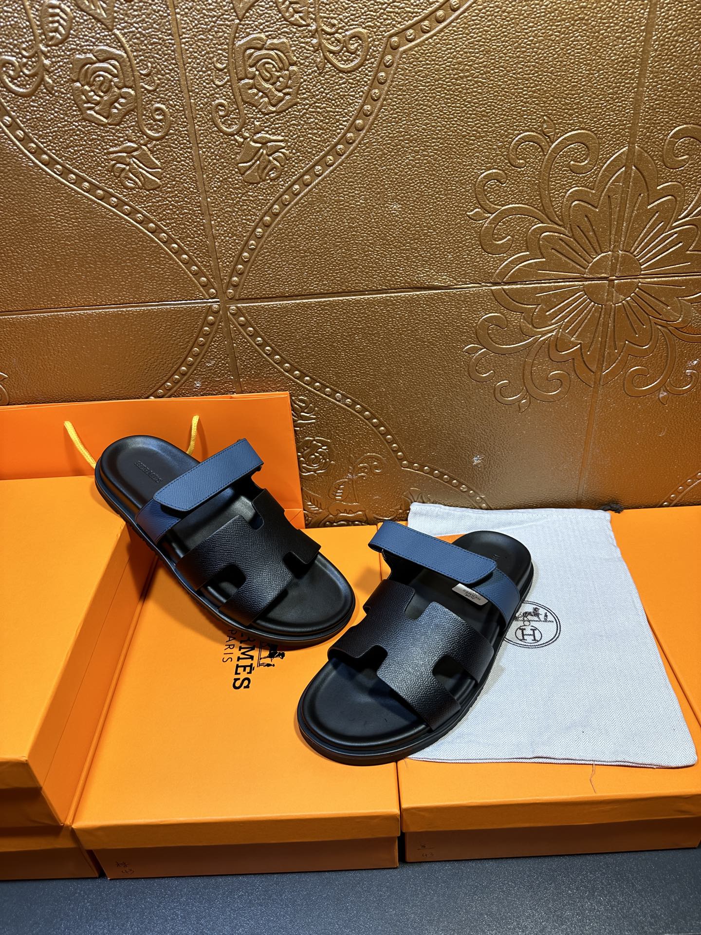 Hermes black slide sandals with blue strap, side view on box