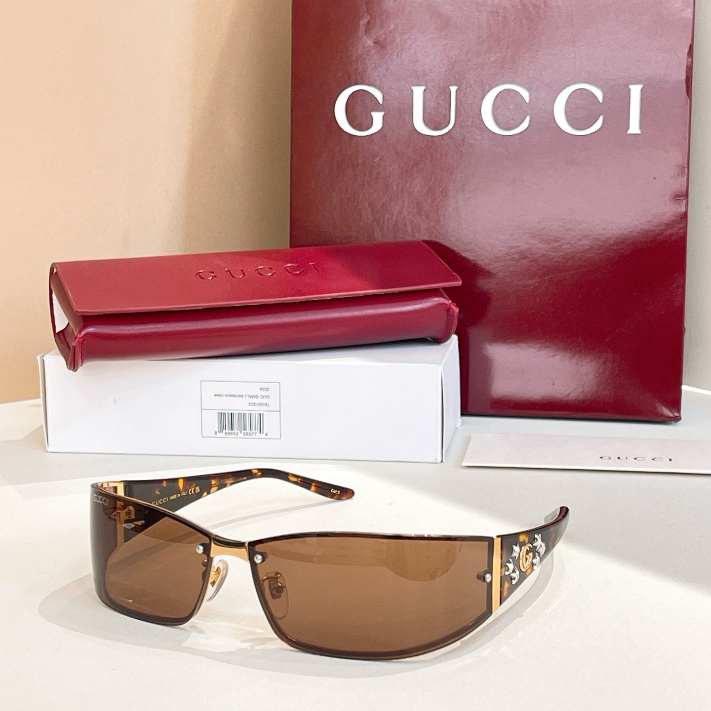 Brown-tinted sunglasses with black frame and gold logo side