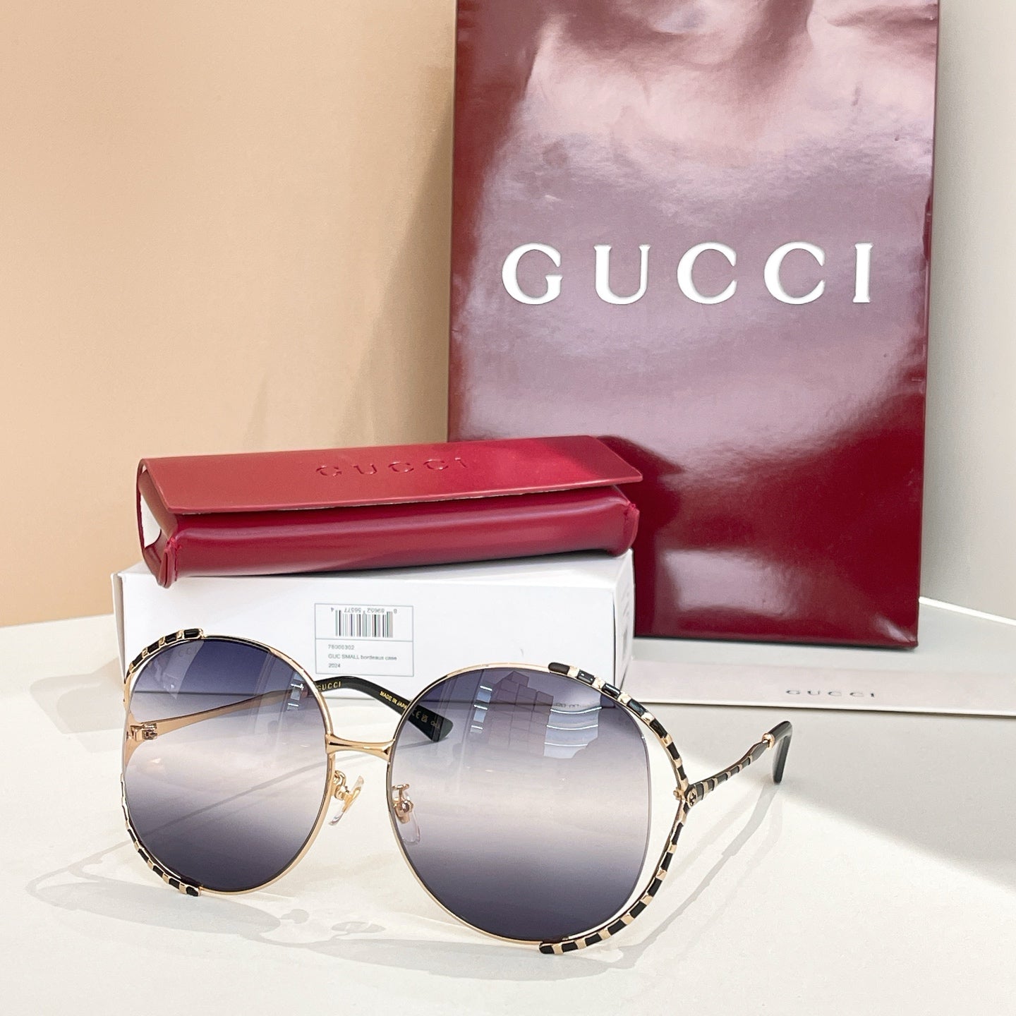Gucci round sunglasses with dark blue lenses, gold frame, and patterned temple arms