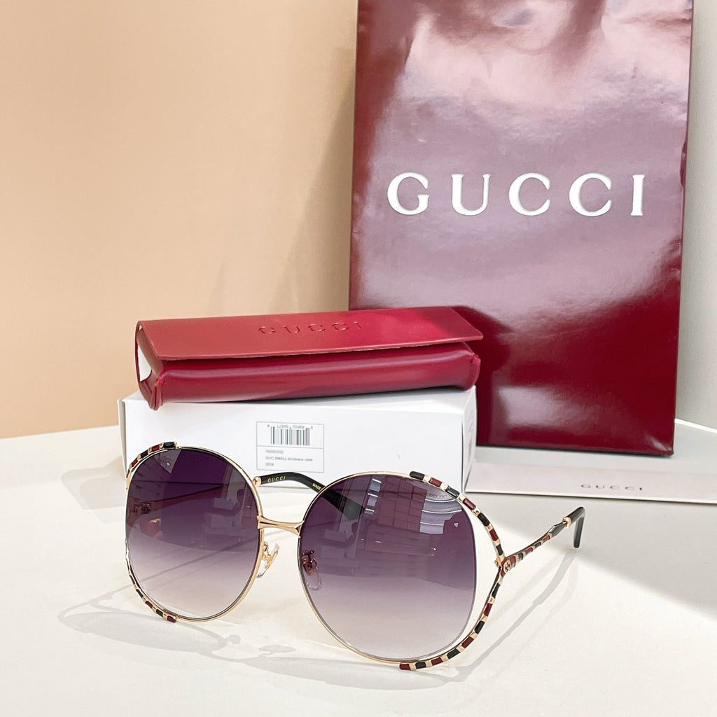 Gucci round sunglasses with dark purple lenses, gold frame, and patterned temple arms
