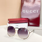 Gucci round sunglasses with dark purple lenses, gold frame, and patterned temple arms