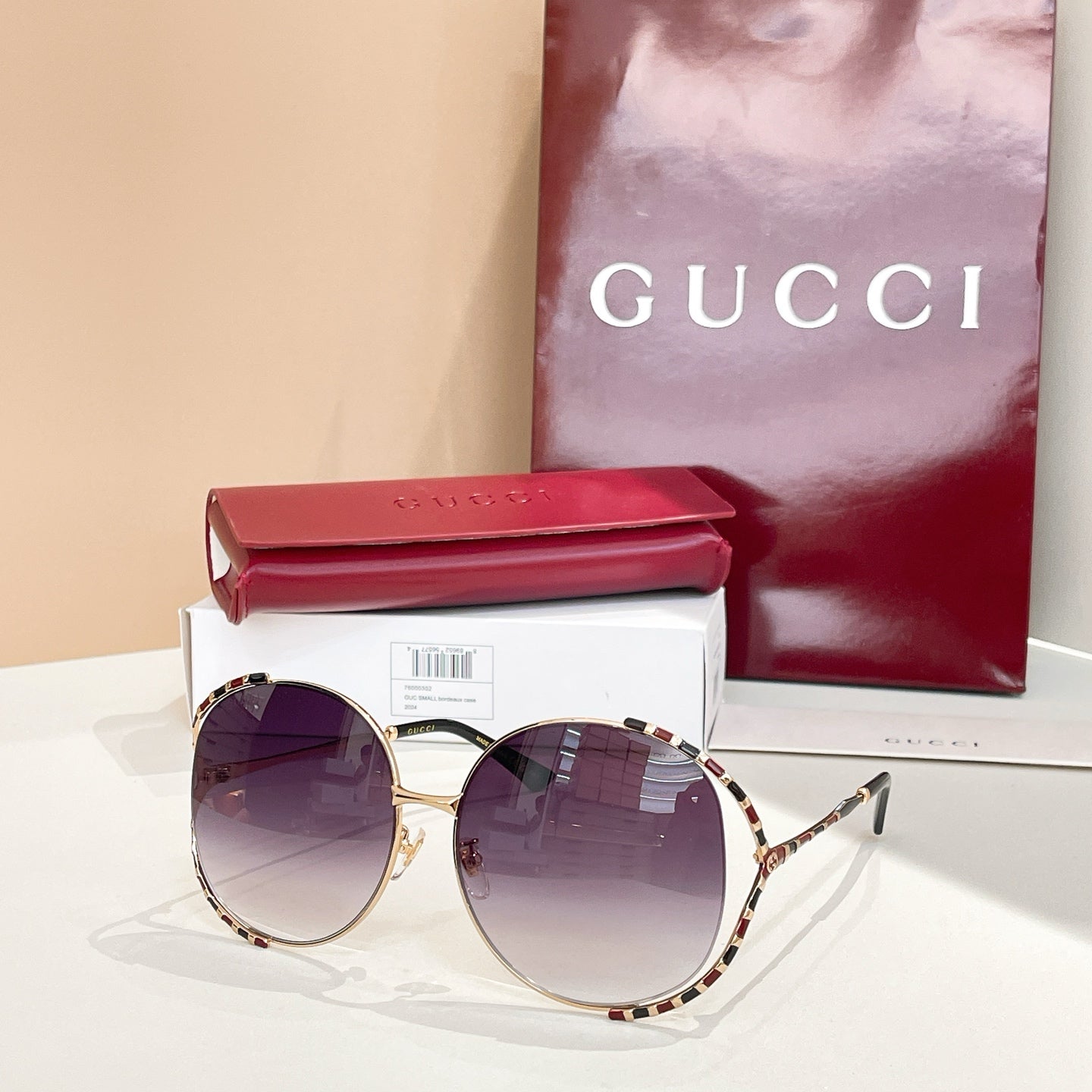 Gucci round sunglasses with dark purple lenses, gold frame, and patterned temple arms