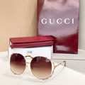 Gucci round sunglasses with dark lenses, gold frame, and patterned temple tips