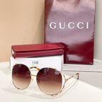 Gucci round sunglasses with dark lenses, gold frame, and patterned temple tips