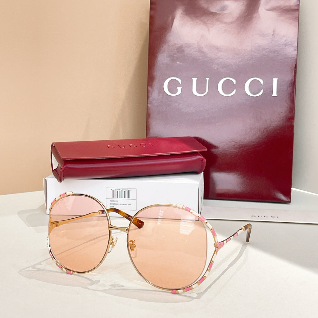 Gucci round sunglasses with pink-tinted lenses, gold frame, and patterned temples