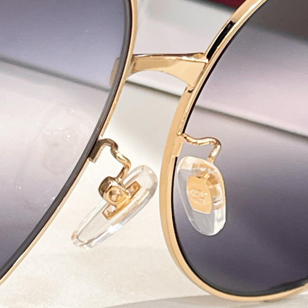 Gucci sunglasses close-up: gold frame and temple detail with dark tinted lens