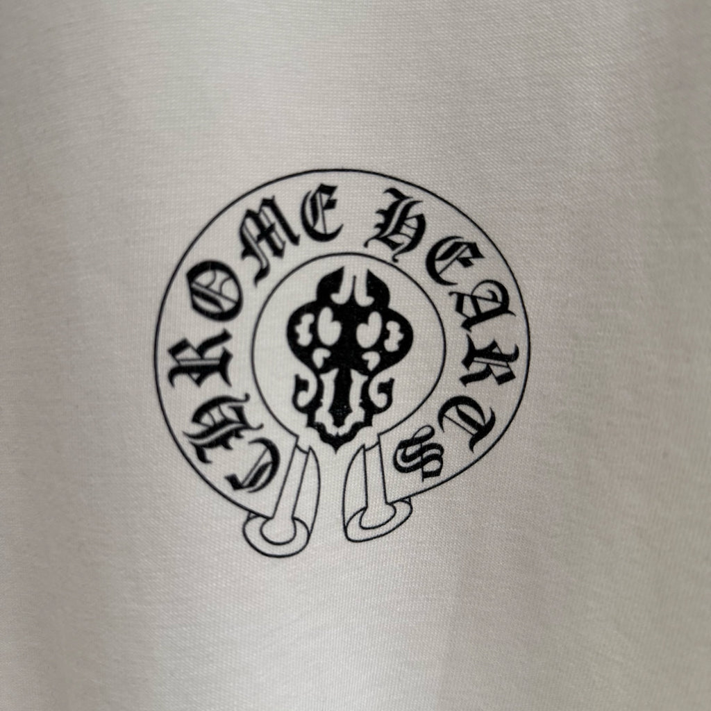 Close-up of circular “Chrome Hearts” emblem print on a white T-shirt