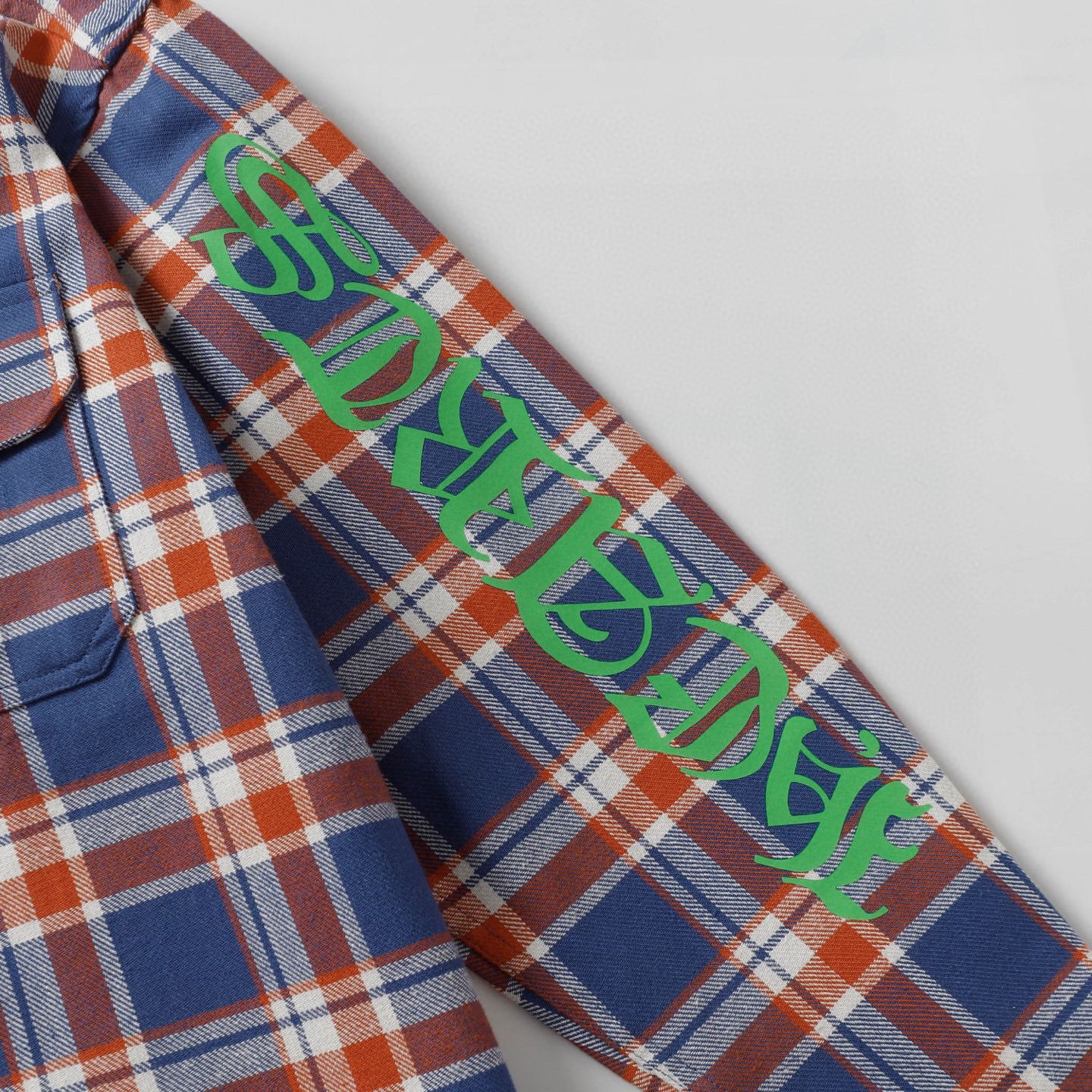 Plaid shirt sleeve with multicolor graphic lettering panel.