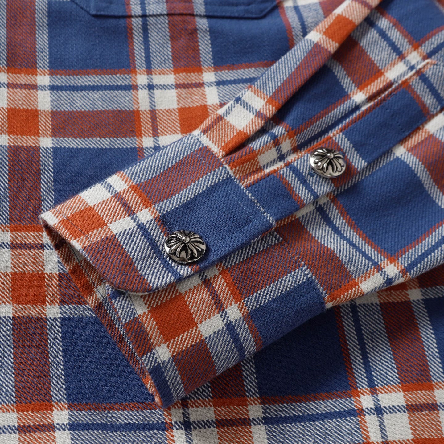 Plaid shirt cuffs with button closures and contrast trim.