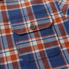 Plaid shirt chest pocket with rounded flap and decorative button.