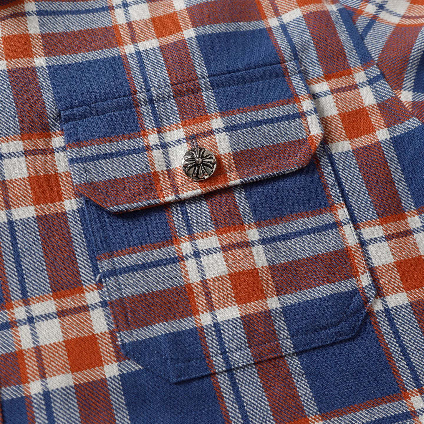 Plaid shirt chest pocket with rounded flap and decorative button.
