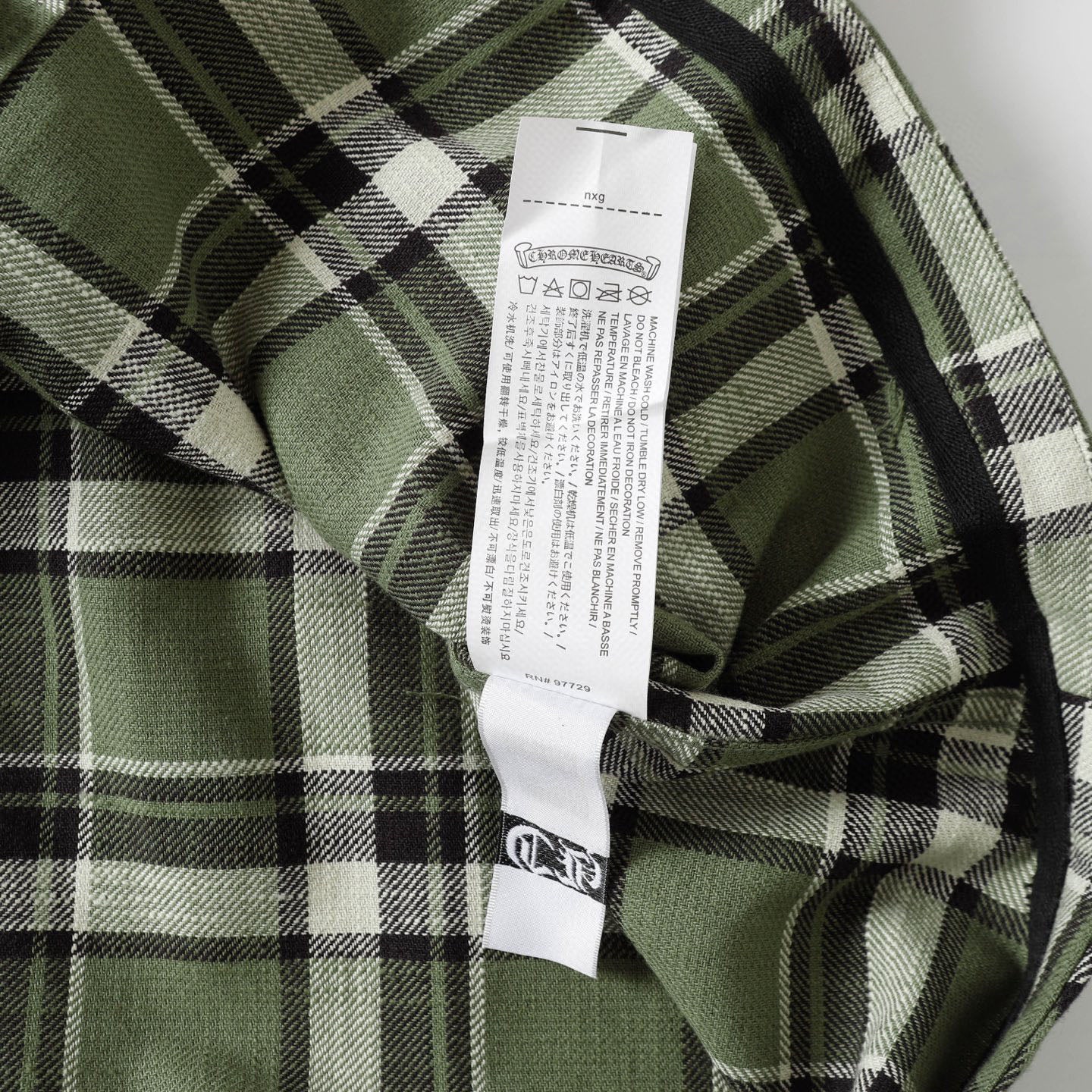 Plaid shirt with interior neck label tag on green, black, and white check fabric