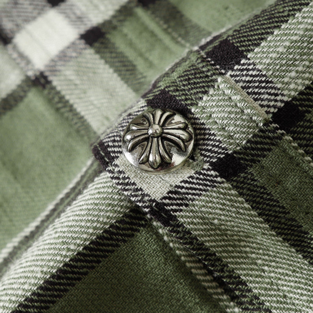 Close-up of plaid shirt button detail on green, black, and white fabric