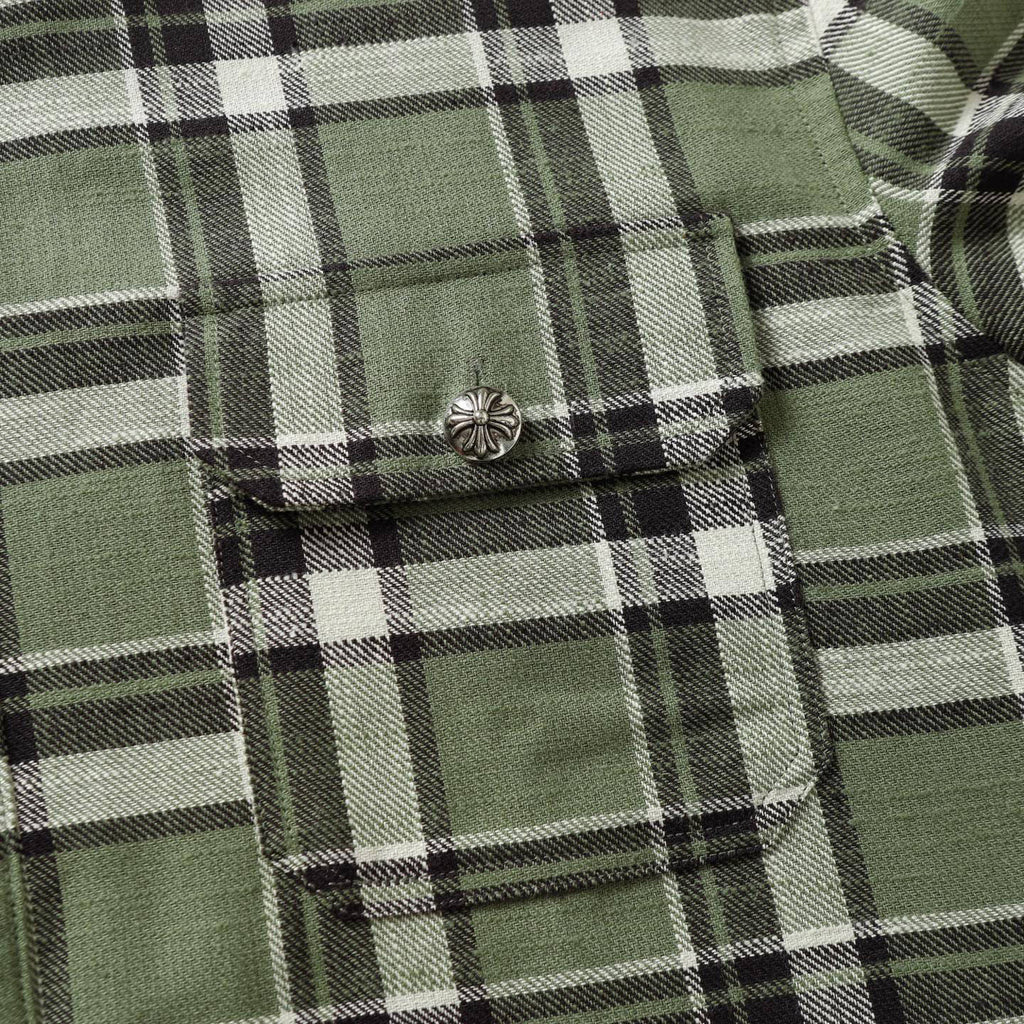 Plaid shirt chest pocket with button detail in green, black, and white checks