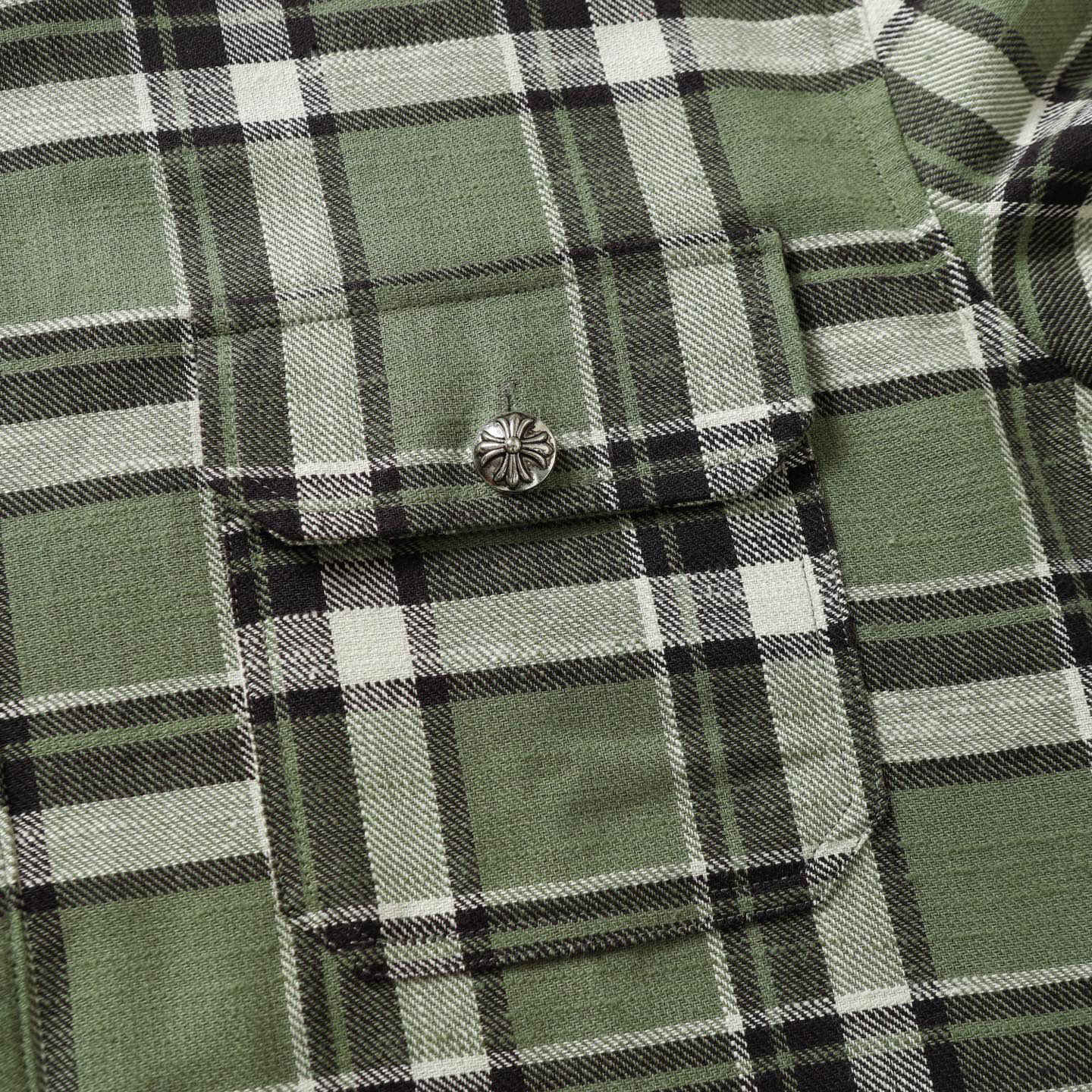 Plaid shirt chest pocket with button detail in green, black, and white checks