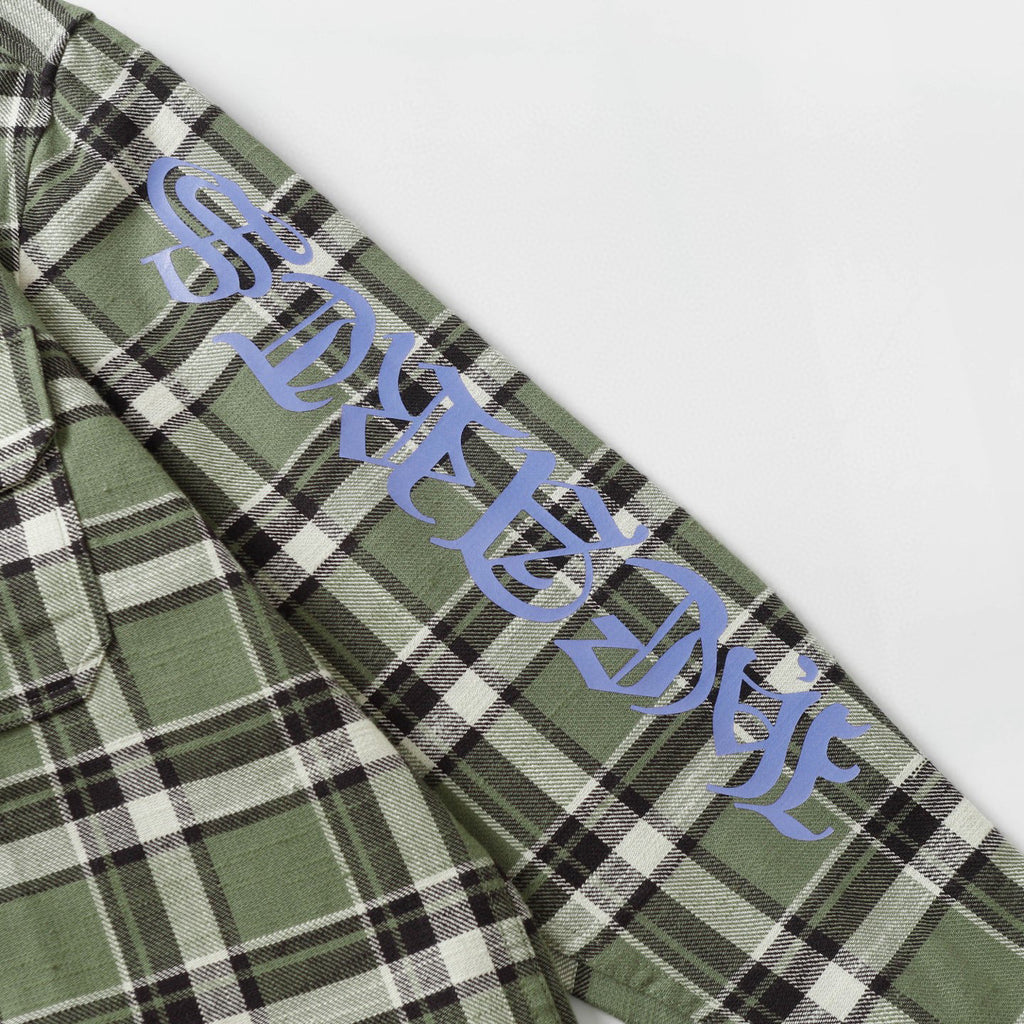 Long-sleeve plaid shirt sleeve with blue script text over green, black, and white checks