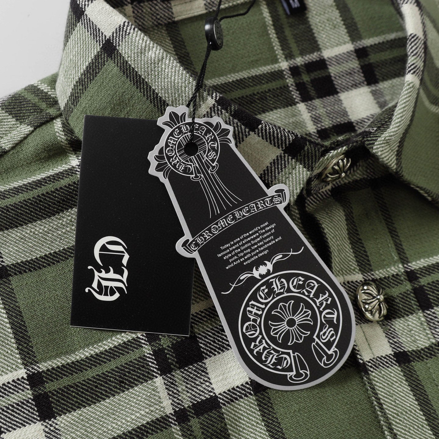 Plaid shirt neck label area with front buttons and metal button details on green fabric