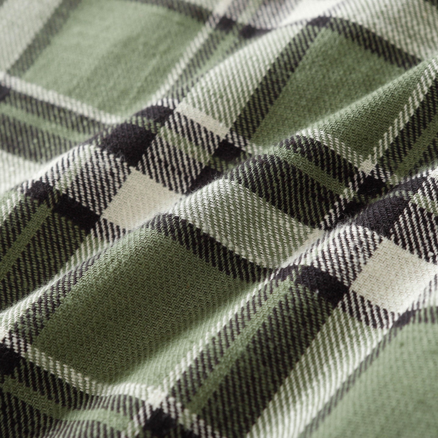 Close-up of green plaid fabric with black and white intersecting stripes