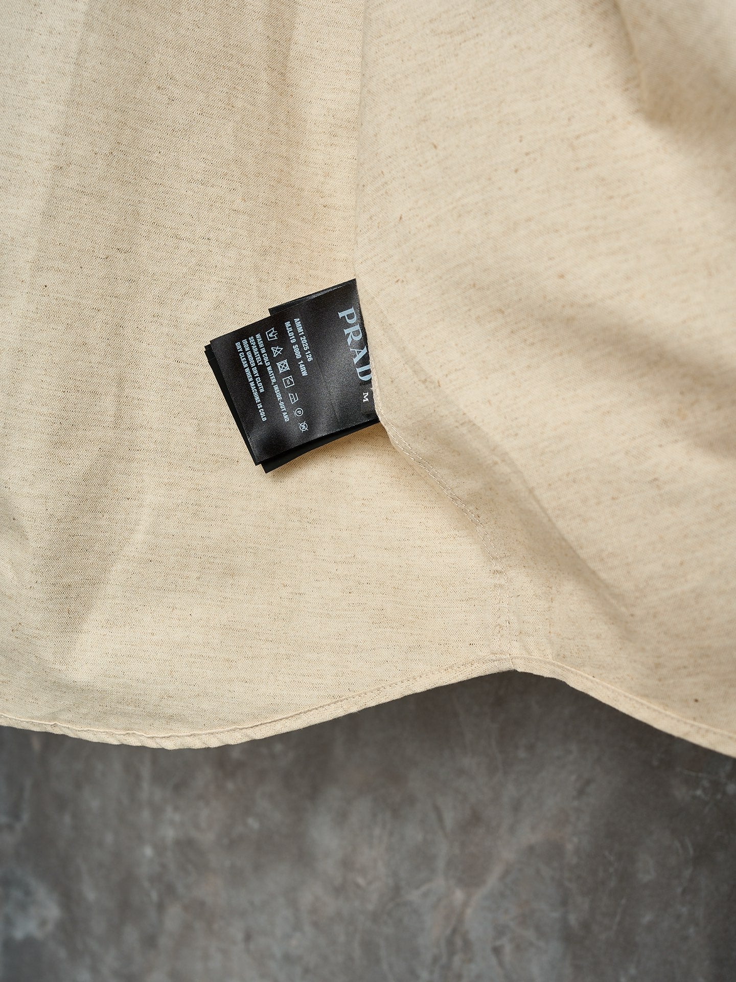 Cream long-sleeve button-up shirt hem with attached product tag