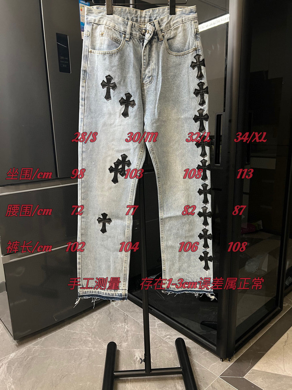 Light wash denim pants with black cross patches shown on display rack